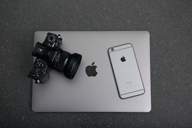 a camera and cellphone resting on top of a closed laptop
