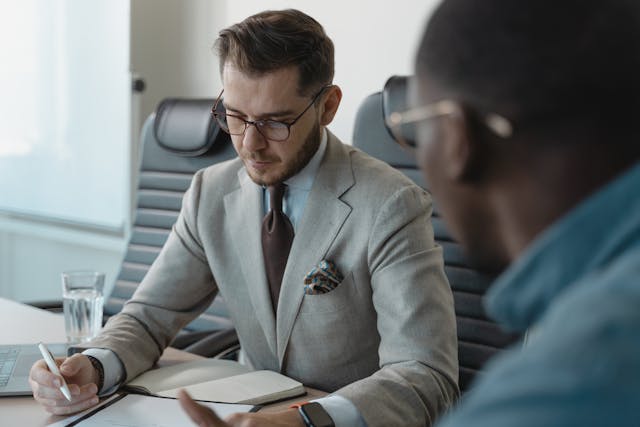 two people sitting in an office looking over documents